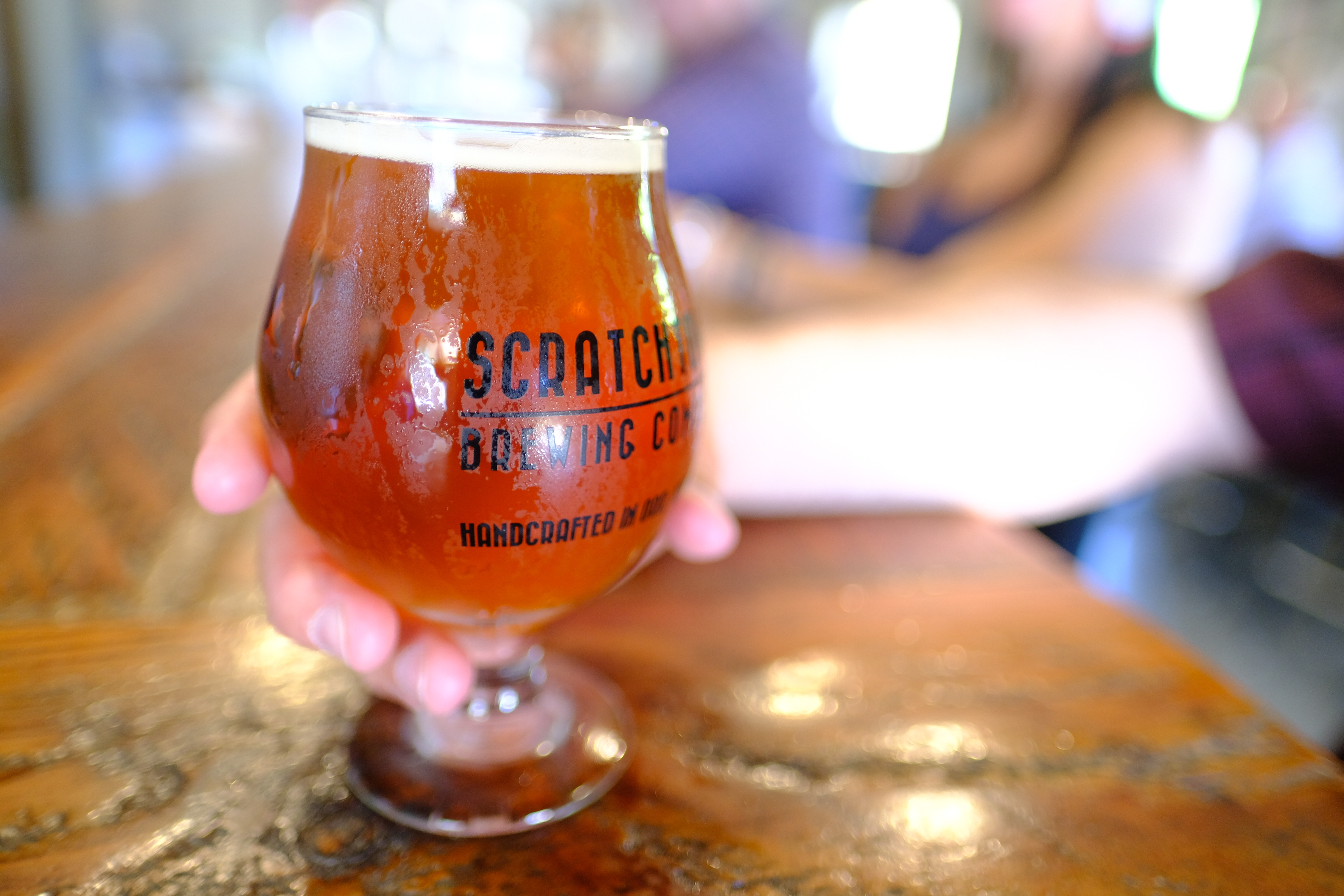 Someone holding a beer at Scratchtown Brewing Company. 
