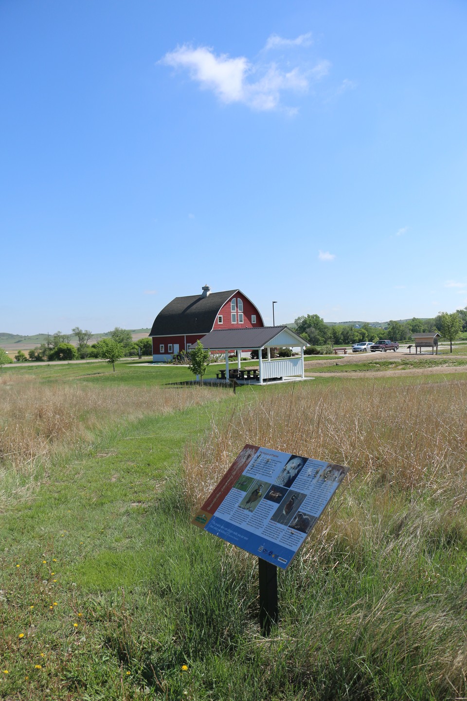 Exterior view of a trail display and Sandhills Journey Scenic Byway Visitor Center inside a large red barn.