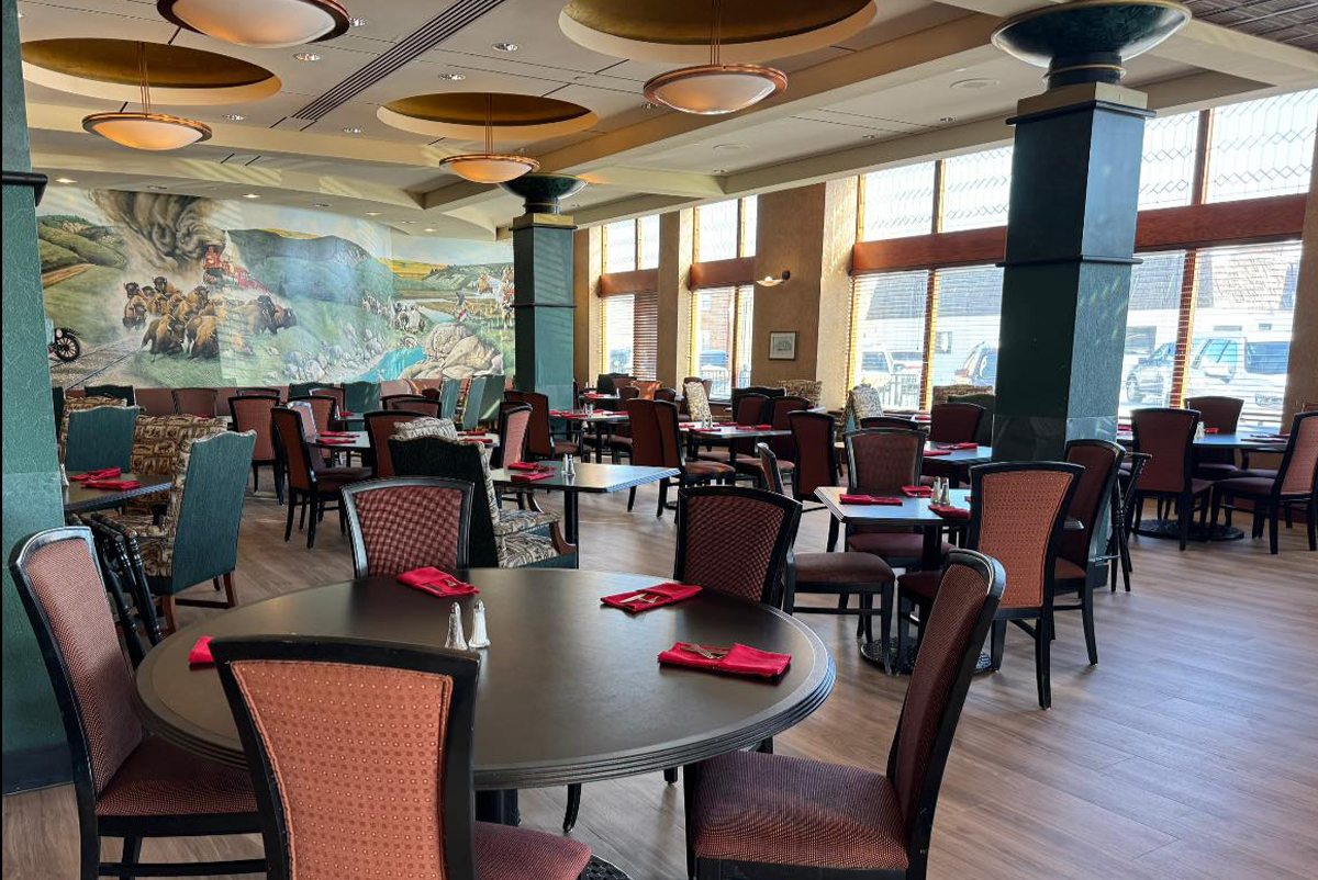 Tables and chairs with place settings inside Duster's Restaurant & Gottberg Brewery with a mural in the background on the far wall.