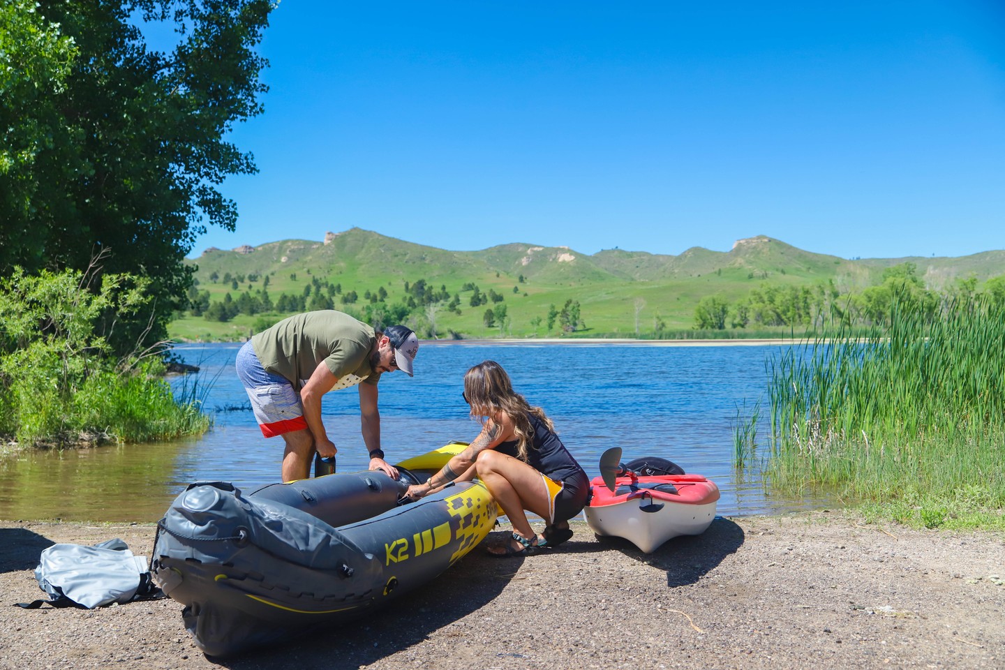 A couple inflating a canoe on the bank of the water at Fort Robinson State Park, with bluffs in the distance.