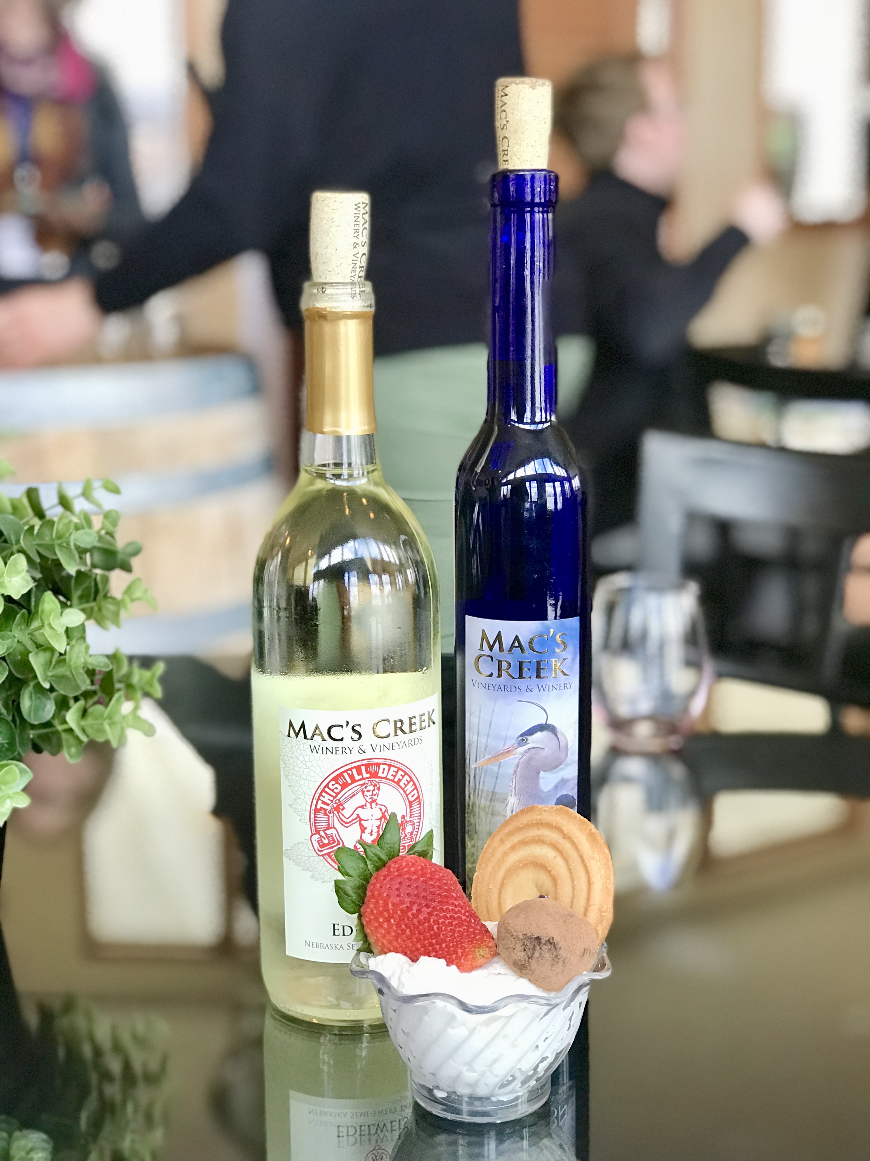Bottles of wine with a dessert in a small dish with cookies and a strawberry on top from Mac's Creek Winery & Brewery.