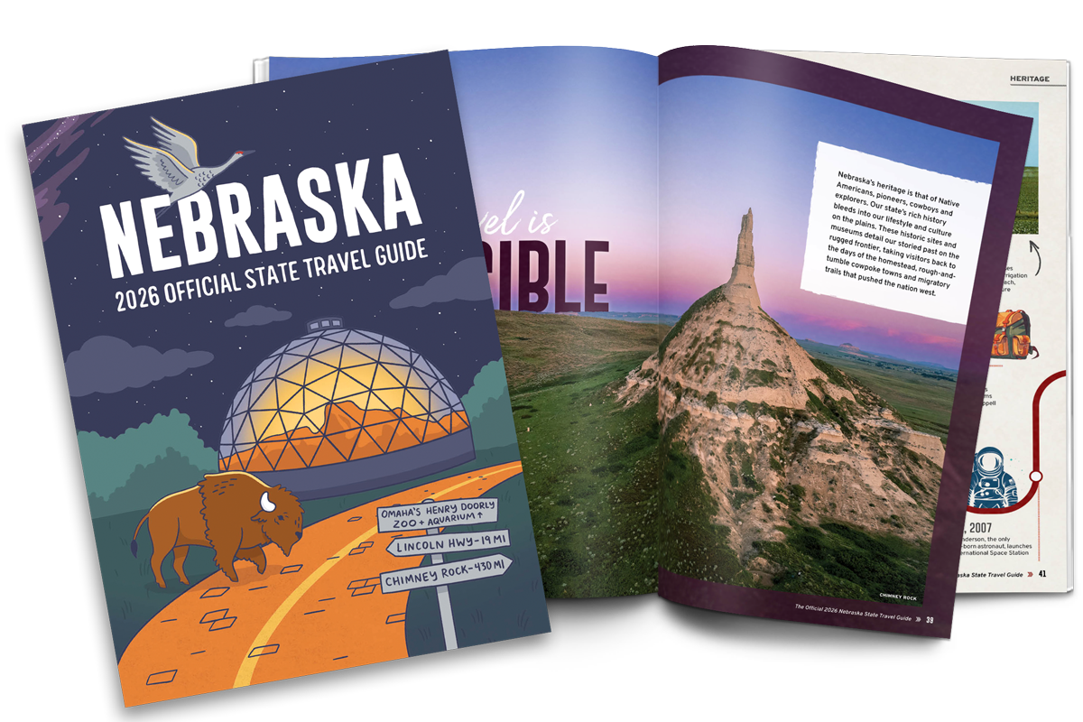 Front cover and internal spread of the 2026 Nebraska Official State Travel Guide.Cover is an illustration of the Desert Dome at Henry Doorly Zoo and Aquarium with a sandhill crane and buffalo on the image. The spread is an image of Chimney Rock.