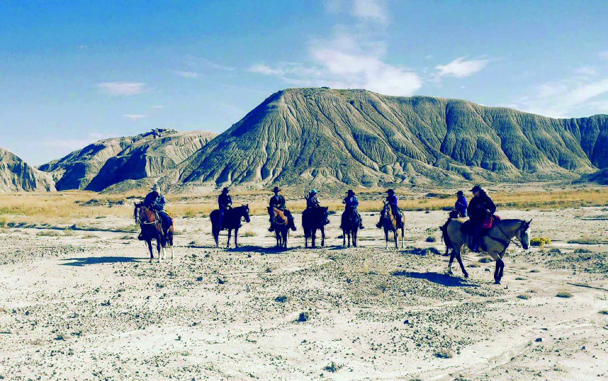 Horseback riding at Our Heritage Guest Ranch with bluffs in the background.