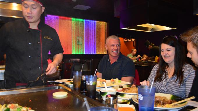 A chef cooking in front of guests at an in-table hibachi flat top at Sakura Sushi & Steakhouse.