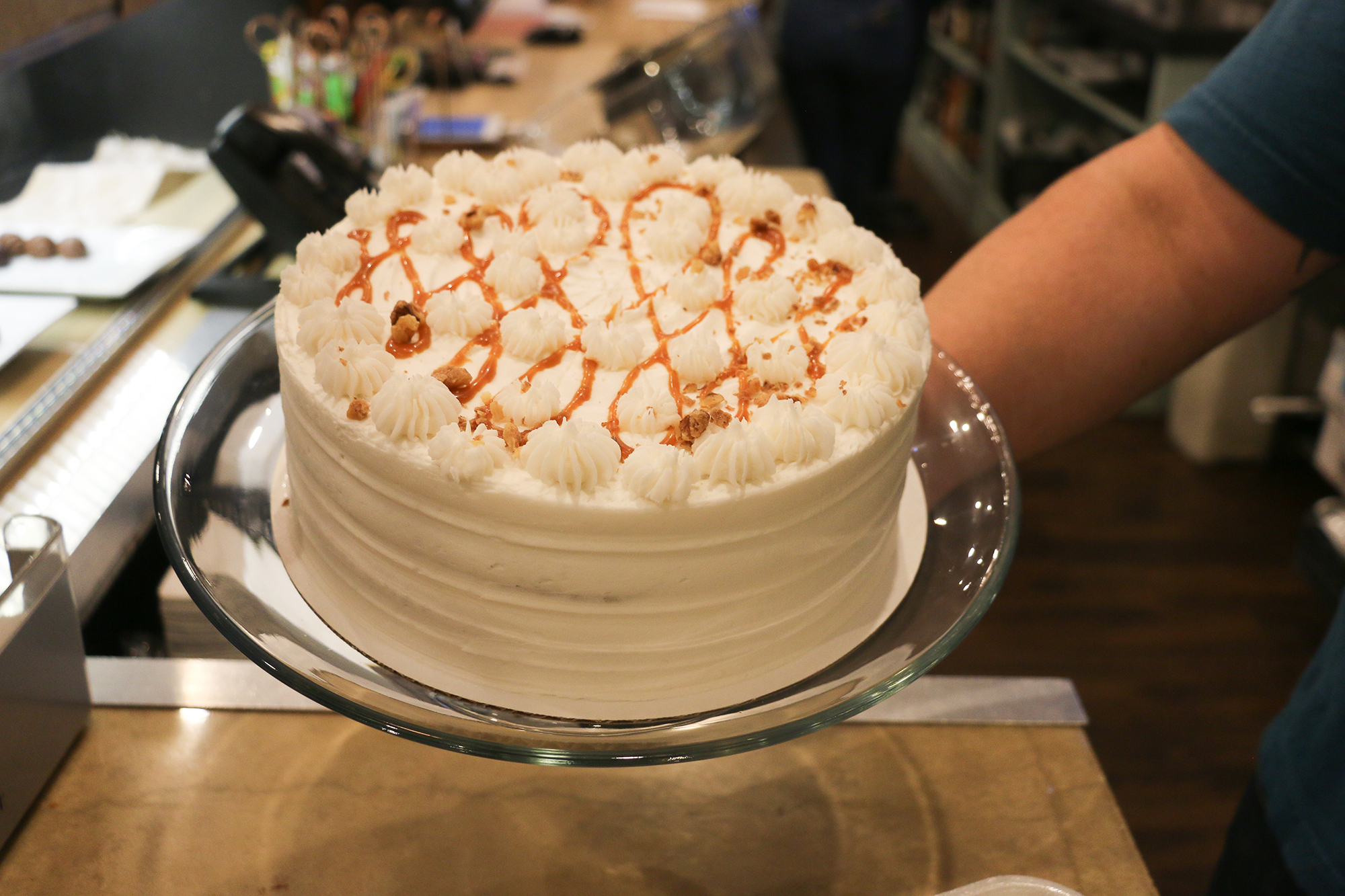 A cake with white icing and caramel-like drizzle from The Chocolate Bar. 