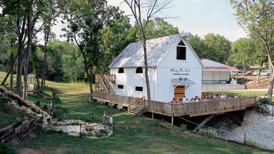 Exterior of Whiskey Run Creek Vineyard & Winery with guests gathered on the patio over a pond.