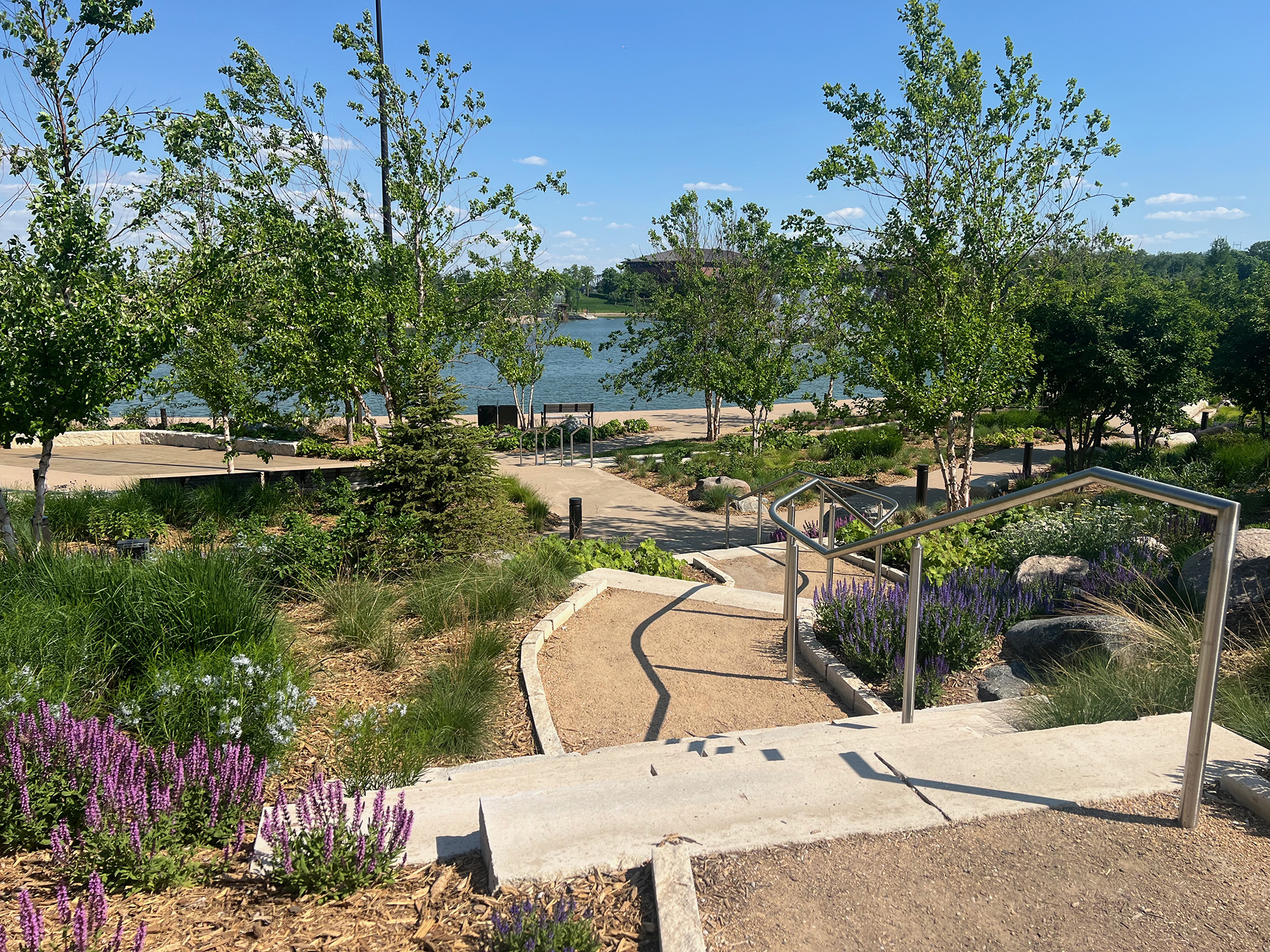 A path leading through landscaping with a body of water in the background at The RiverFront in Omaha.