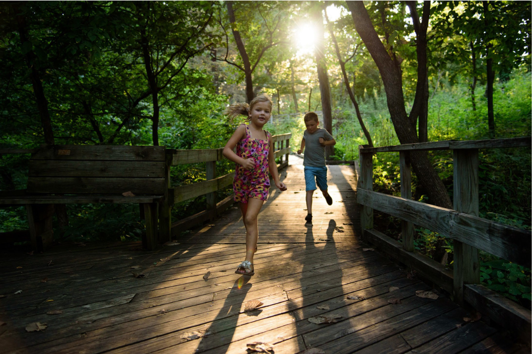 Two kids running on a boardwalk at Fontenelle Forest in Omaha.