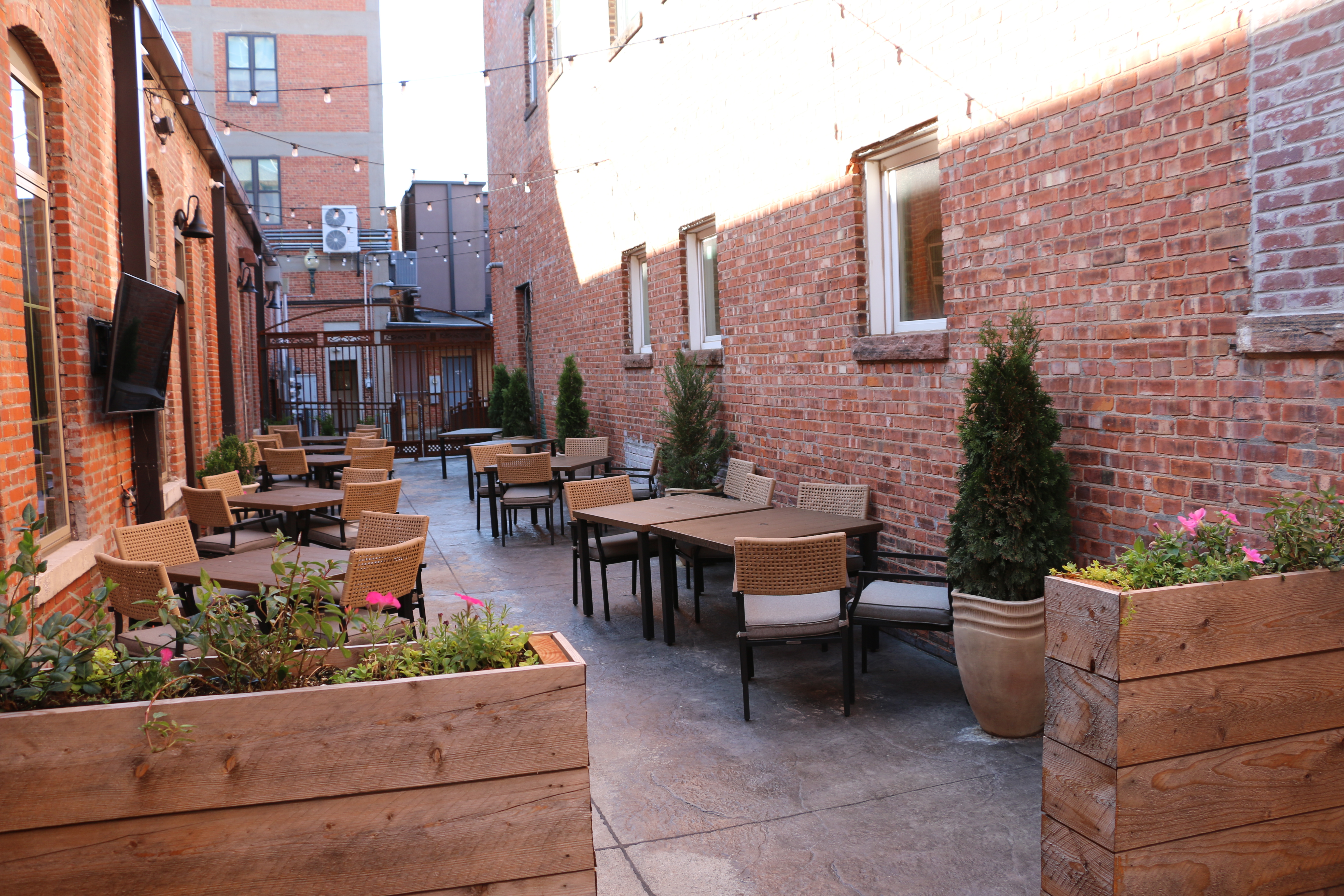 The patio setup with tables, chairs, plants and a tv at Henry J's