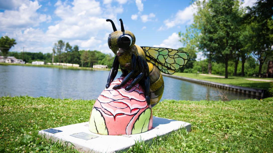 Bee sculpture "Honeybees in the Heartland" next to a body of water in Auburn