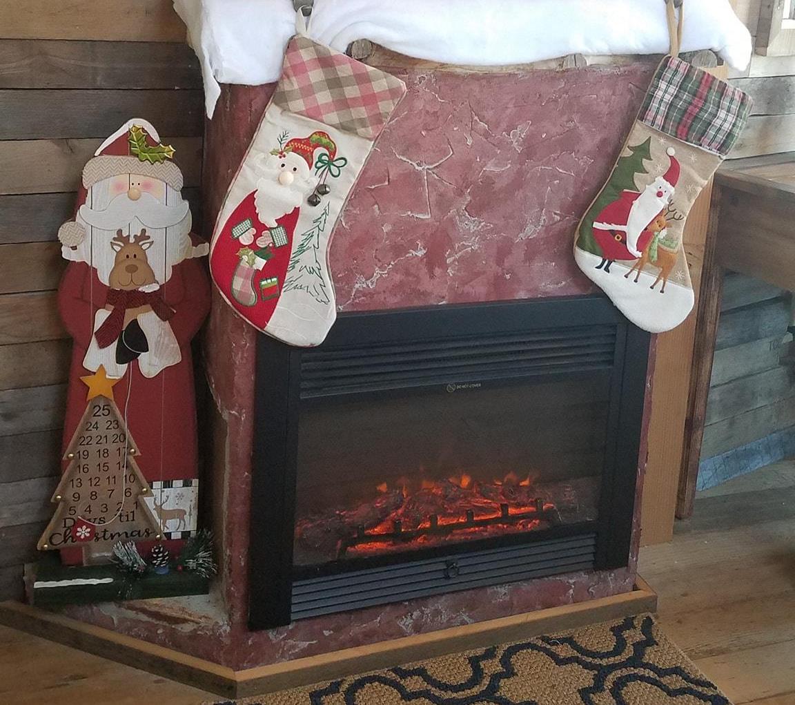 Kottage Knection fireplace with stockings hanging and a Santa sign next to it.