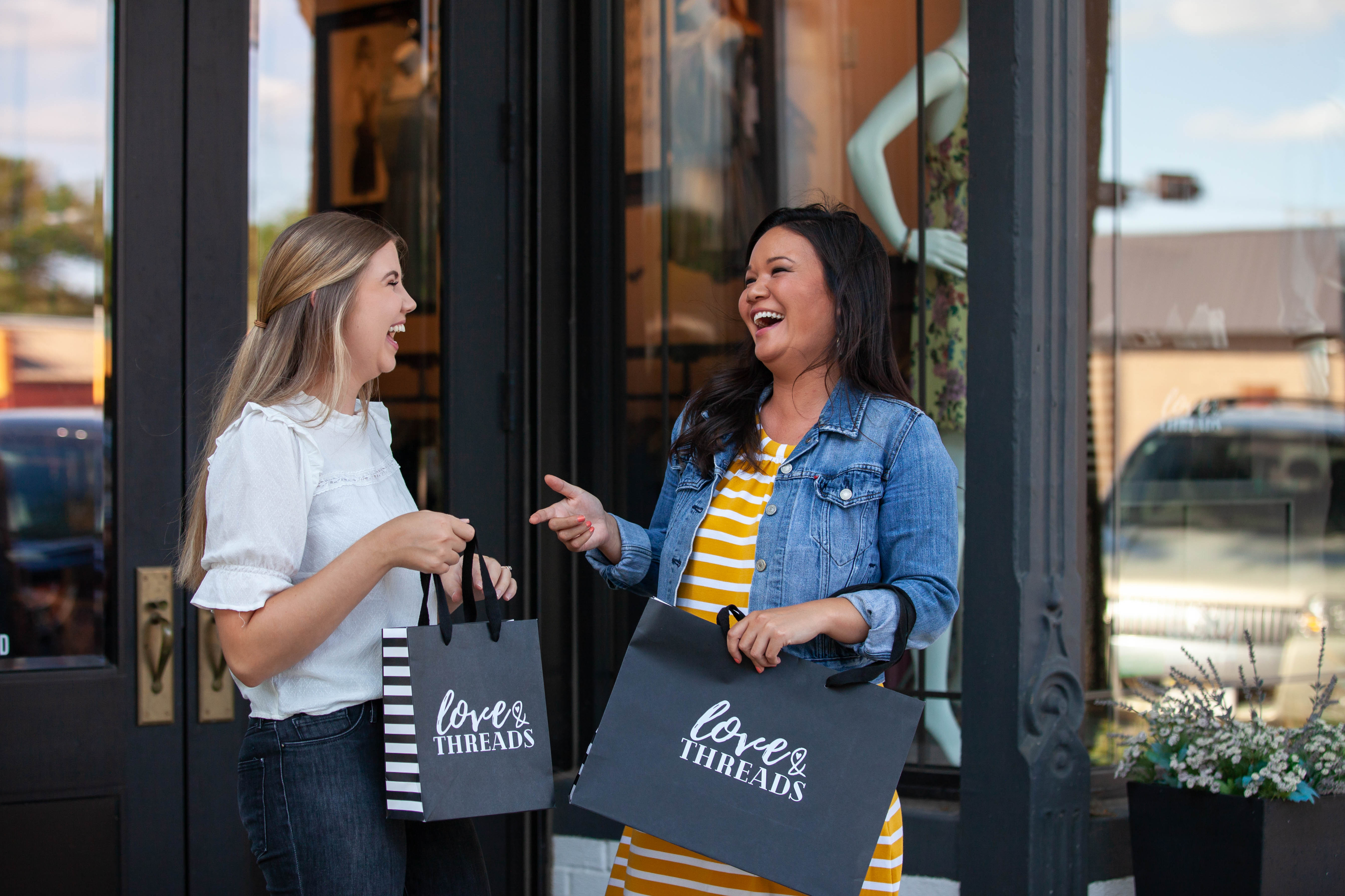 Two customers with shopping bags from Love & Threads.