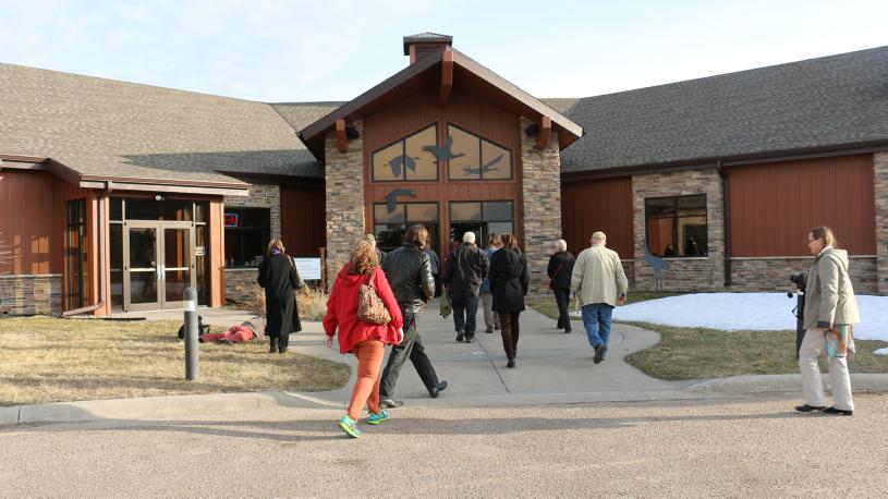 Exterior of Crane Trust Nature & Visitor Center, with multiple guests walking into the main entrance.